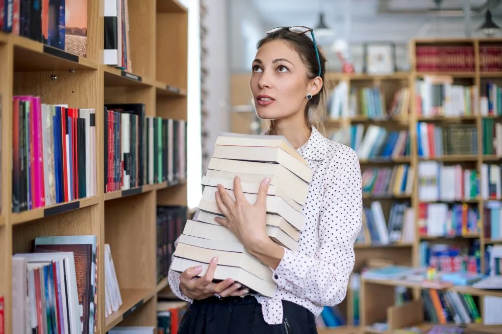 young-woman-with-a-stack-of-books-in-library-1024x683